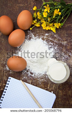 eggs, flour, sour cream, cottage cheese and notepads recipes are on the table