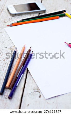 Colored pencils, cell phone and paper on the desk