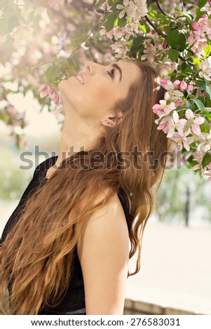 Woman in spring blossom. Young naturally beautiful woman near the blooming tree in spring time. Eco beauty and health concept.