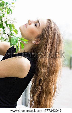 Woman in spring blossom. Young naturally beautiful woman near the blooming tree in spring time. Eco beauty and health concept.