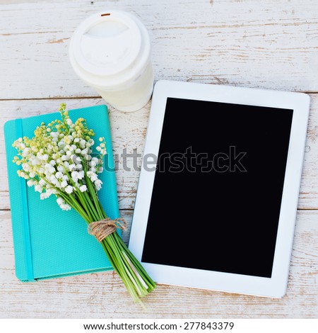diary, a tablet computerand  lilies of valley on the table