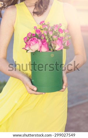 Bouquet of pink roses in a box  in the hands of the girl.