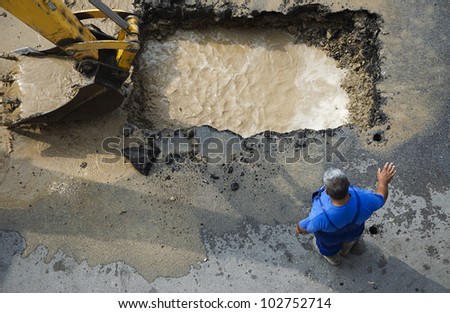 Excavator and worker repairing damaged water supply