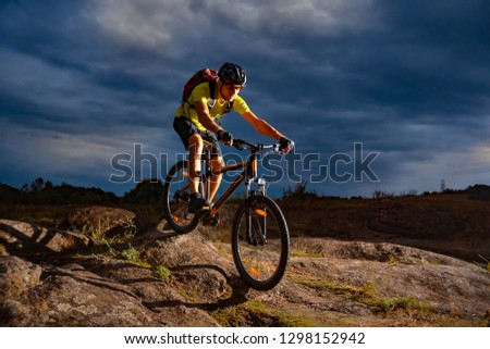Cyclist Riding the Mountain Bike on the Rocky Trail in the Evening. Extreme Sport and Enduro Biking Concept.