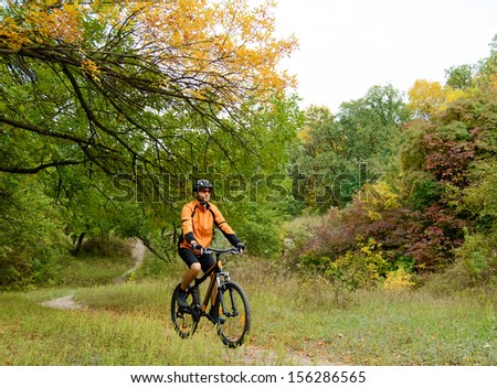Cyclist Riding the Bike on the Trail in the Beautiful Autumn Forest