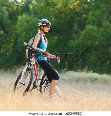 Young Attractive Woman Resting with Bike on the Beautiful Meadow in the Forest