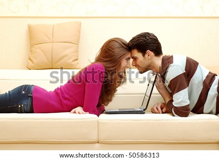 stock photo : Young happy couple working on laptop and smiling at home
