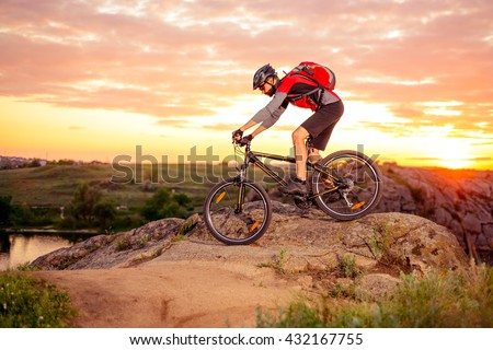 Cyclist Riding the Bike Down Hill on the Mountain Rocky Trail at Sunset. Extreme Sports