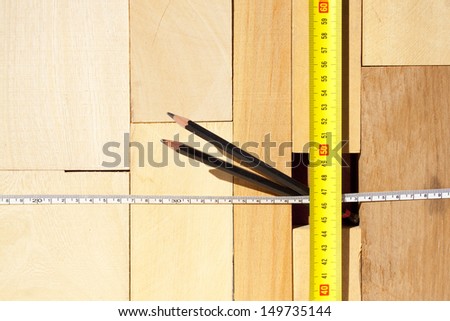 A pile of various size blocks of wood  with two tape measures and two pencils