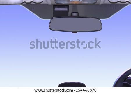 Framed view of sky from interior of vehicle showing rear-view mirror