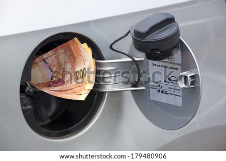 concept of south african banknotes feeding into petrol tank indicating petrol price increase
