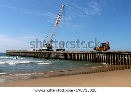 DURBAN, SOUTH AFRICA - MAY 3, 2014: Workers mobile crane backhoe  pay loader at pier construction site on North Beach in Durban South Africa
