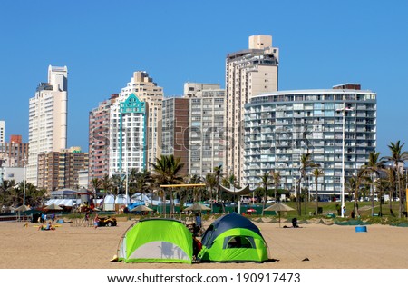 DURBAN, SOUTH AFRICA - MAY 3, 2014: Many people and green tents pitched on North beach against city skyline in Durban South Africa