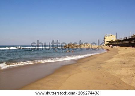 DURBAN, SOUTH AFRICA - JULY 11, 2014: Many unknown people enjoy low tide at Umdloti beach in Durban, South Africa