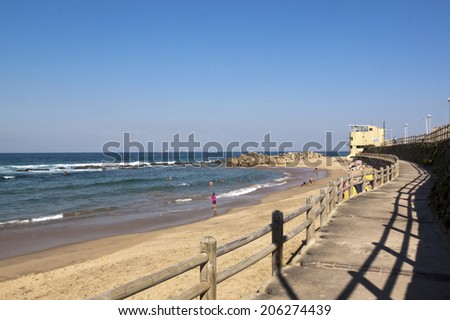 DURBAN, SOUTH AFRICA - JULY 11, 2014: View from concrete walkway of many unknown people enjoying  low tide at Umdloti beach in Durban, South Africa