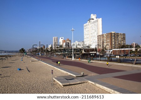DURBAN, SOUTH AFRICA - JULY 23, 2013: Early morning, people walk along promenade on Golden Mile beach front in Durban South Africa