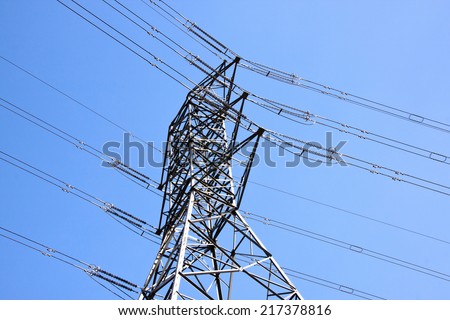 closeup of steel pylon supporting heavy electric power cables against blue sky