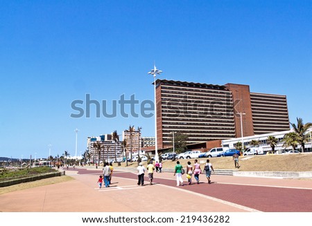 DURBAN, SOUTH AFRICA - SEPTEMBER 21, 2014: Many unknown people walk along promenade in front of residential complexes on \