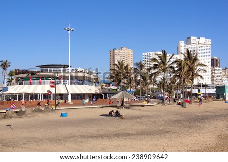 DURBAN, SOUTH AFRICA - DECEMBER 18, 2014: Many unknown people on early morning North Beach against commercial and residential Buildings in Durban, South Africa