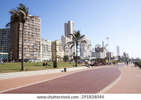 DURBAN, SOUTH AFRICA - JUNE 7, 2015: Many unknown people on beach front promenade against city skyline in Durban, South Africa