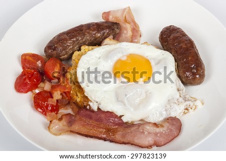 Studio shot traditional breakfast of egg, bacon, sausages, fried tomato and toast