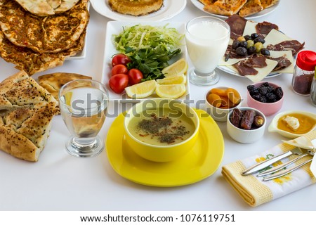Stylish Ramadan (iftar) table.Traditional Turkish lentil soup in yellow soup set,fancy fabric napkin on the white table with other foods.Islamic holiday concept.