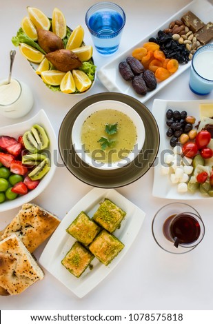 Traditional Ramadan (iftar) table with soup,Turkish baklava,tea,date fruits,fresh fruits,pide,black olives and stuffed meatball on the white surface.Top view,isolated.