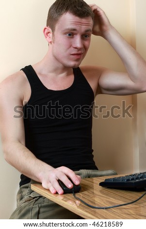 Young man scratches his head, as his computer is not giving him what he wants.