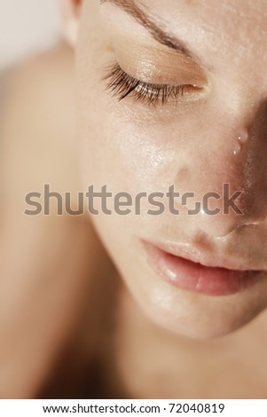 Close-up of beautiful wet woman face with water drop.