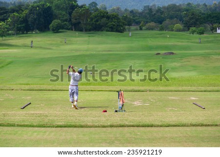 Male golf player teeing off golf balls from tee box, wonderful cloud in background.