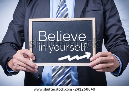businessman holding a blackboard with believe in yourself text