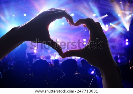 Crowd of Audience at during a concert with a heart shaped hands shadow