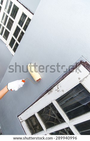 hand glove holding paint brush white painting home wall