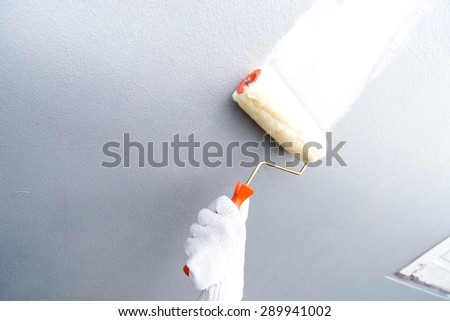 Hand glove holding painting roller white painting home wall