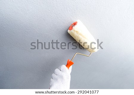 wall in a new building as a background and paint roller in a working position.