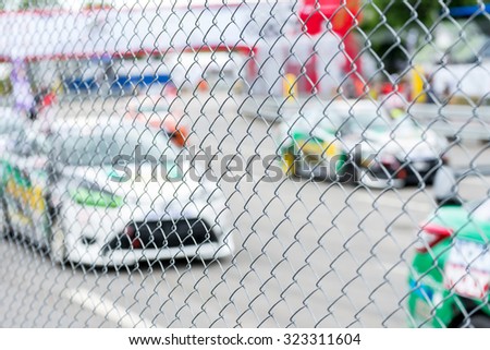 blurred image of racing car on track view from behind fence