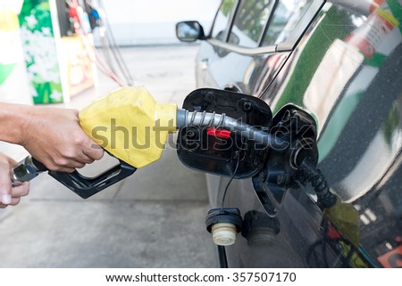 Pumping gas at gas pump. Closeup of man pumping gasoline fuel in car at gas station