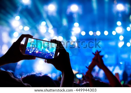 audience crowd with the power of live concert, silhouette hands of people use smart phones enjoying the concert.