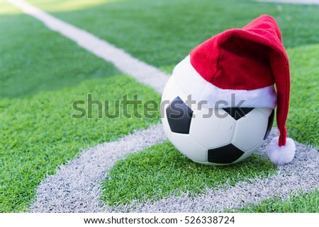 Santa Claus red hat on soccer ball at green grass