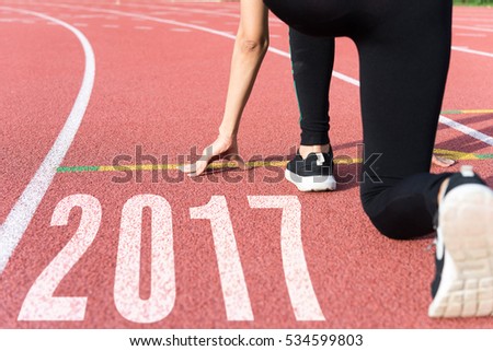 Athlete on starting line waiting for the start in running track with text 2017 year, Start to new year