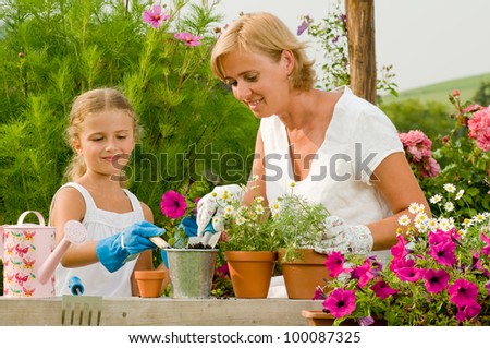 Garden, planting concept - mother with daughter planting flowers into the flowerpot