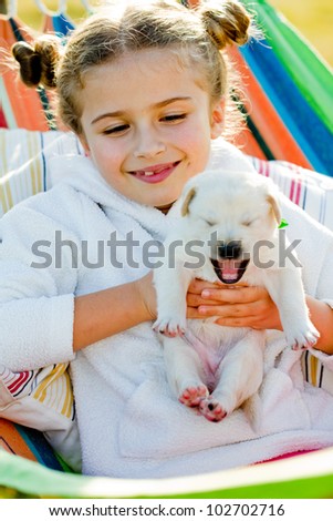 Puppy, child - lovely girl with cute Labrador puppy in hammock