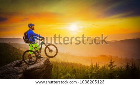 Mountain biker riding at sunset on bike in summer mountains forest landscape. Man cycling MTB flow trail track. Outdoor sport activity.