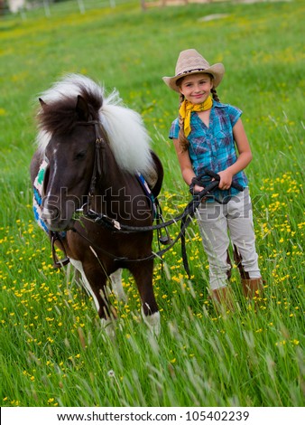 Pony and girl - lovely cowgirl  is grazing little pony on the meadow