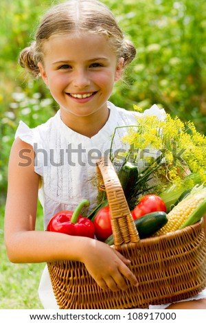 Harvests of vegetables - lovely kid with the basket of ecological harvests