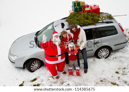 Waiting for Christmas, Santa Claus - family is carrying Christmas tree and gifts on the roof of the car