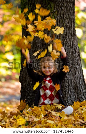 Autumn fun, happy child - lovely girl has a fun in autumn leaves