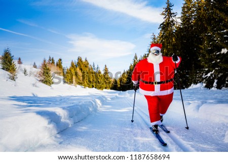 Santa Claus with Christmas suits with classic  nordic ski in snowy winter mountain ski resort landscape in sunny day, New Year\'s or xmas is coming.