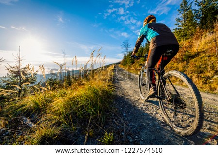 Cycling woman riding on bike in autumn mountains forest landscape. Woman cycling MTB flow trail track. Outdoor sport activity.