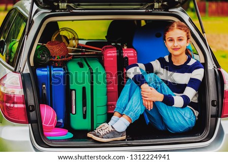 Summer vacation, young girl in the car trunk  is ready for travel for family vacation.